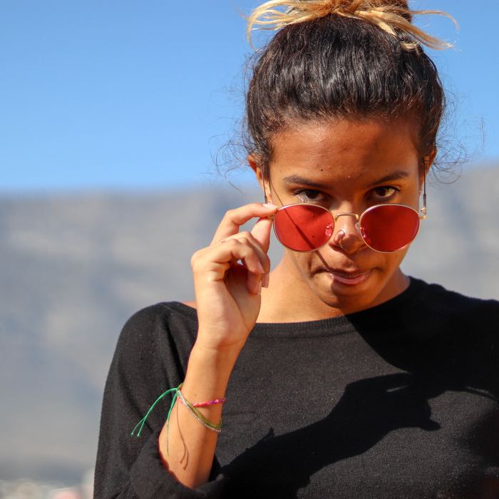 Femme baissant ses lunettes rouges, sourire en coin